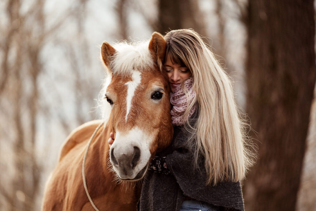 Frau umarmt Pferd